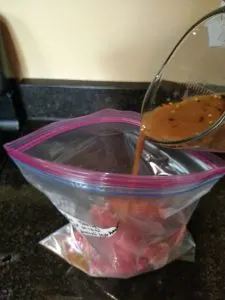 pouring liquid over meat for Crock Pot Beef and Broccoli Freezer Meal